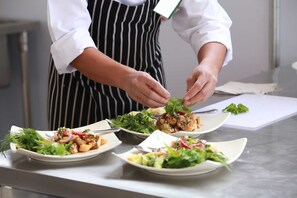 A chef preparing dishes on a stainless steel counter.