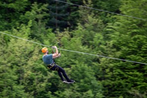 A person ziplining through a forested area.