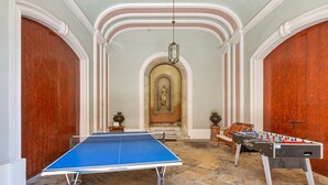 Una habitación con mesa de ping pong, mesa de fútbol y una estatua al fondo.