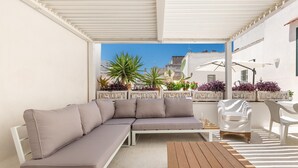 Un espacio exterior moderno con un sofá, una mesa de madera y una silla.