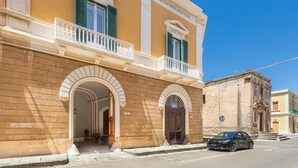 Un edificio histórico con puertas de arco y un balcón con barandilla blanca.