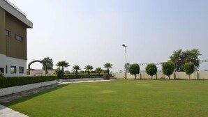 A well-maintained grassy area with a modern building, a clear sky, and a streetlight.