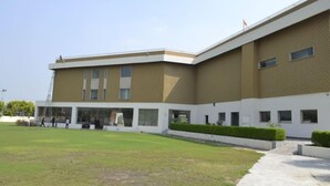 A modern building with a flat roof, large windows, and a paved courtyard.