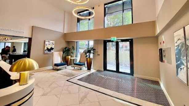 A hotel lobby with a reception desk, seating area, and large windows. - 2-bed Luxury Apartment in Birmingham City Center (Birmingham)