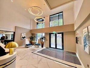 Un hall d’hôtel comprenant un comptoir d’accueil, un espace salon et de grandes fenêtres.
