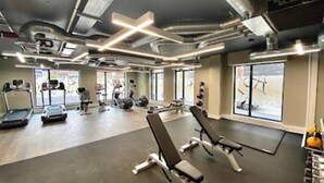 A gym with exercise equipment, benches, and a large window. - 2-bed Luxury Apartment in Birmingham City Center (Birmingham)