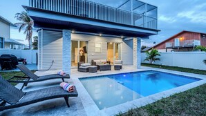A modern house with a swimming pool, outdoor seating, and a covered patio. - Renovated Naples Beach Home w/ Pool & Lanai (Naples)