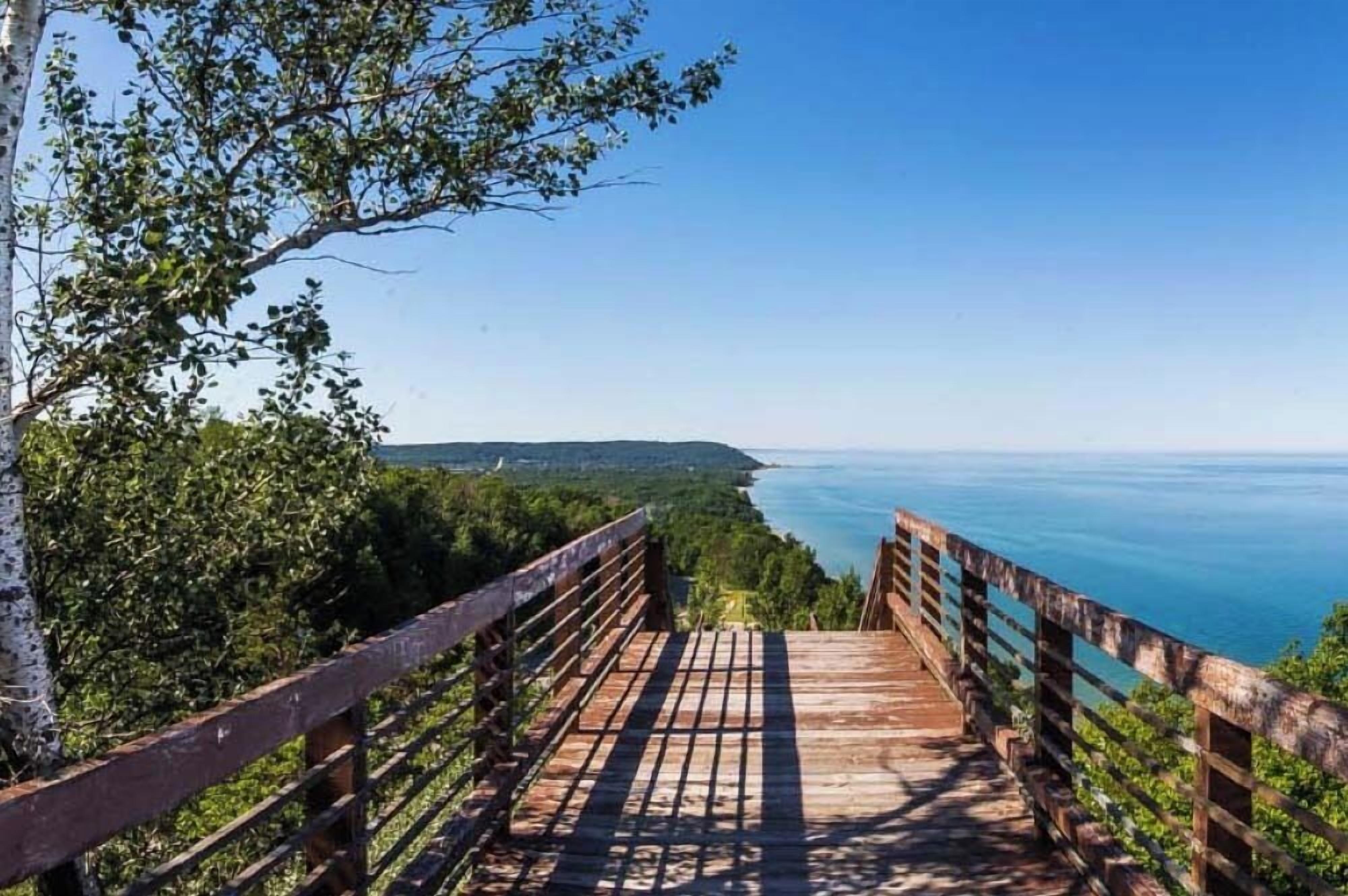 A wooden staircase leading to a viewpoint overlooking a coastal landscape.