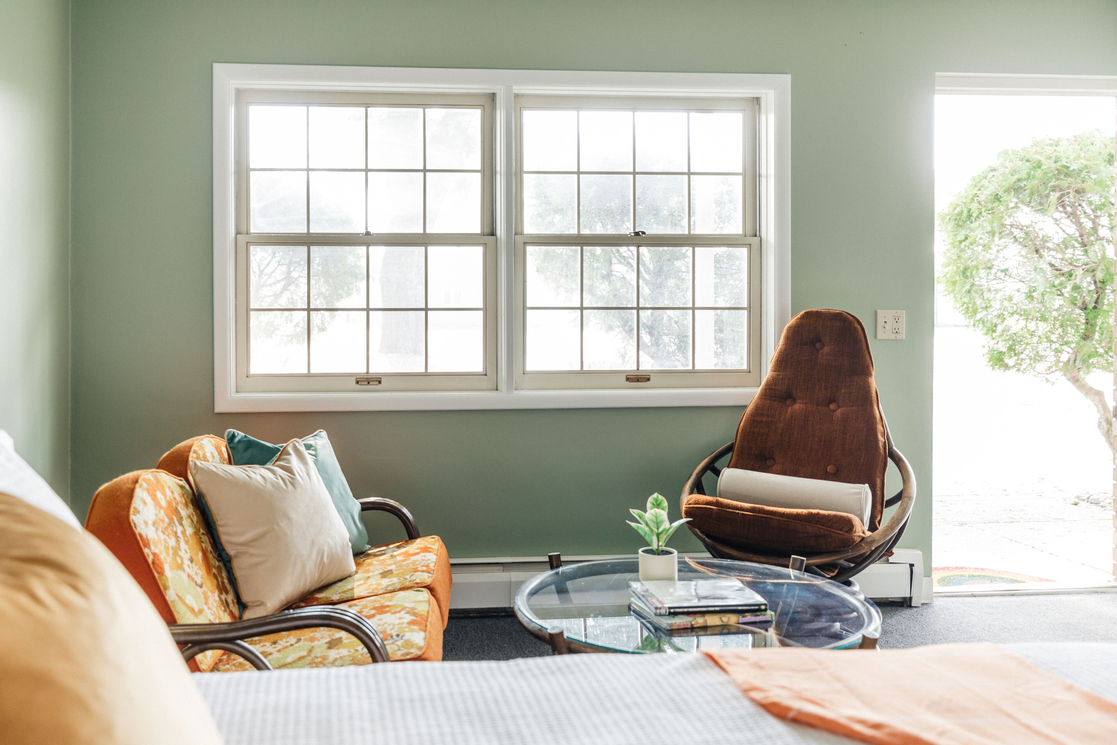 A room with a sofa, armchair, and a small table with books and a plant.