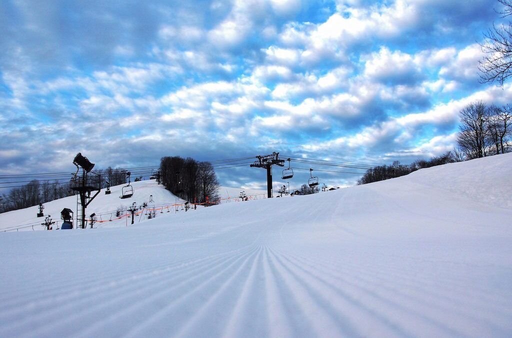 A snow-covered ski slope with ski lifts and a clear sky.