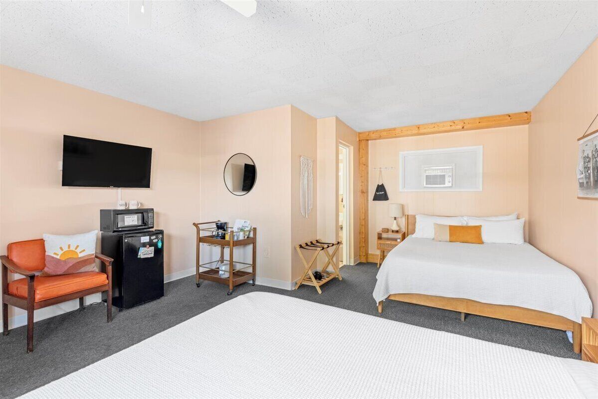 Una camera d'albergo con un letto, una televisione, un forno a microonde, un tavolino e una sedia.