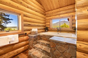 A log cabin bathroom with a stone sink, wooden walls, and a window with a mountain view. - Humphreys Peak View Luxury Log Cabin (Fort Valley)