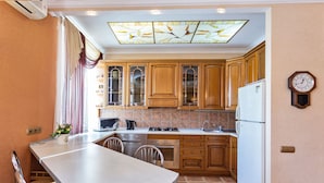 A compact kitchen with wooden cabinets, a white refrigerator, a microwave, and a stove. - Stylish and new apartments  (Minsk)