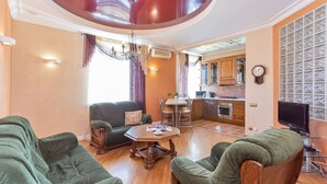 A living room with green sofas, a wooden coffee table, and a dining area with a table and chairs. - Stylish and new apartments  (Minsk)
