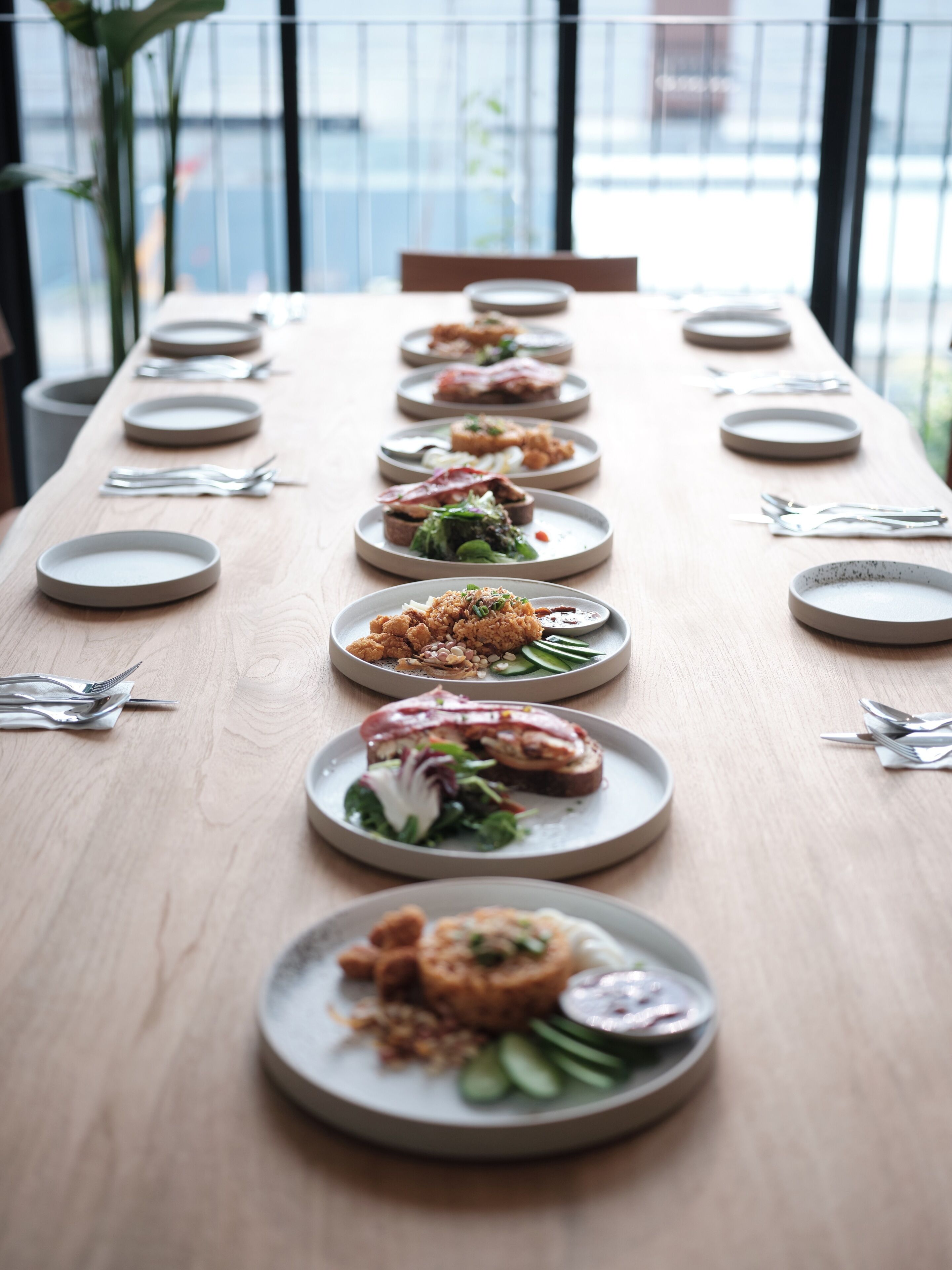 Une longue table à manger, avec des assiettes remplies de nourriture, disposées en rangée.