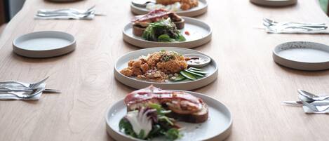 Une longue table à manger, avec des assiettes remplies de nourriture, disposées en rangée.