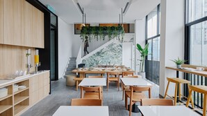 A modern restaurant with wooden furniture, a staircase, and large windows. - Lloyd's Inn Kuala Lumpur (Kuala Lumpur)