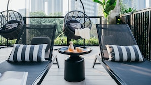 A rooftop terrace with two lounge chairs, a round table with a tray, and a city skyline view. - Lloyd's Inn Kuala Lumpur (Kuala Lumpur)