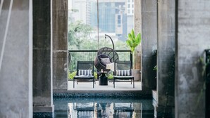 A balcony with two wicker chairs, a small table, and a potted plant. - Lloyd's Inn Kuala Lumpur (Kuala Lumpur)
