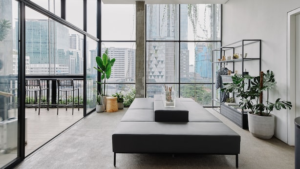 A modern living room with a large window, a sofa, a ceiling fan, and a plant. - Lloyd's Inn Kuala Lumpur (Kuala Lumpur)
