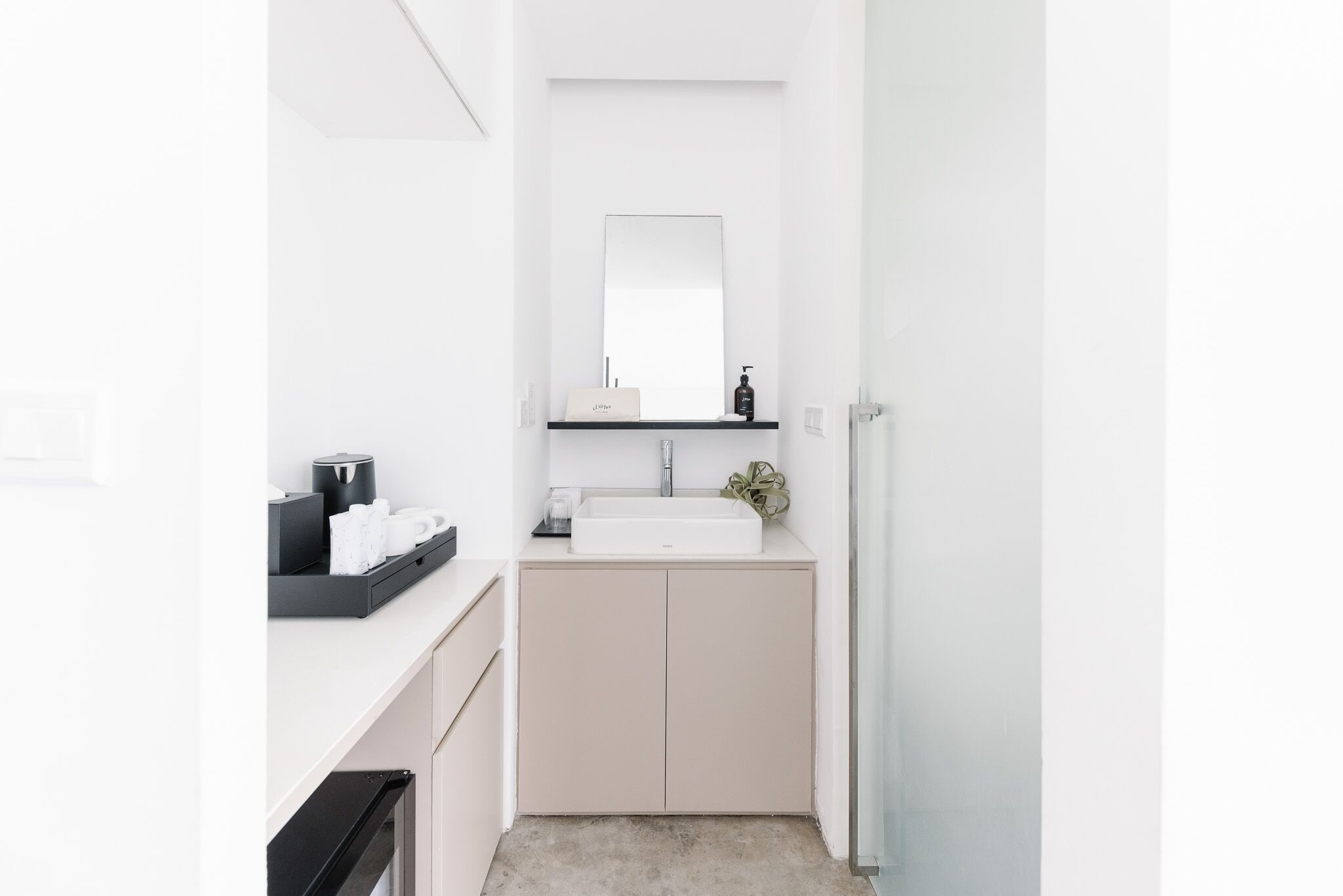 A modern bathroom with a white sink, a mirror, and a black countertop.