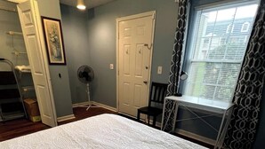 A bedroom with a large bed, a door, a fan, and a window with patterned curtains. - AU Condo Getaway Across From Vet School - Kitchen, Pools, Queen BR, Pets Welcome (Auburn)