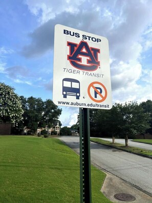 A bus stop sign with the Auburn University logo, a bus icon, and a no parking symbol. - AU Condo Getaway Across From Vet School - Kitchen, Pools, Queen BR, Pets Welcome (Auburn)
