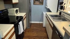 A compact kitchen with a microwave, refrigerator, stove, and dishwasher. - AU Condo Getaway Across From Vet School - Kitchen, Pools, Queen BR, Pets Welcome (Auburn)