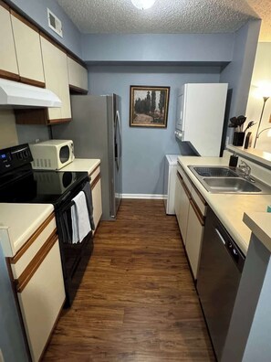 A compact kitchen with a microwave, refrigerator, stove, and dishwasher. - AU Condo Getaway Across From Vet School - Kitchen, Pools, Queen BR, Pets Welcome (Auburn)