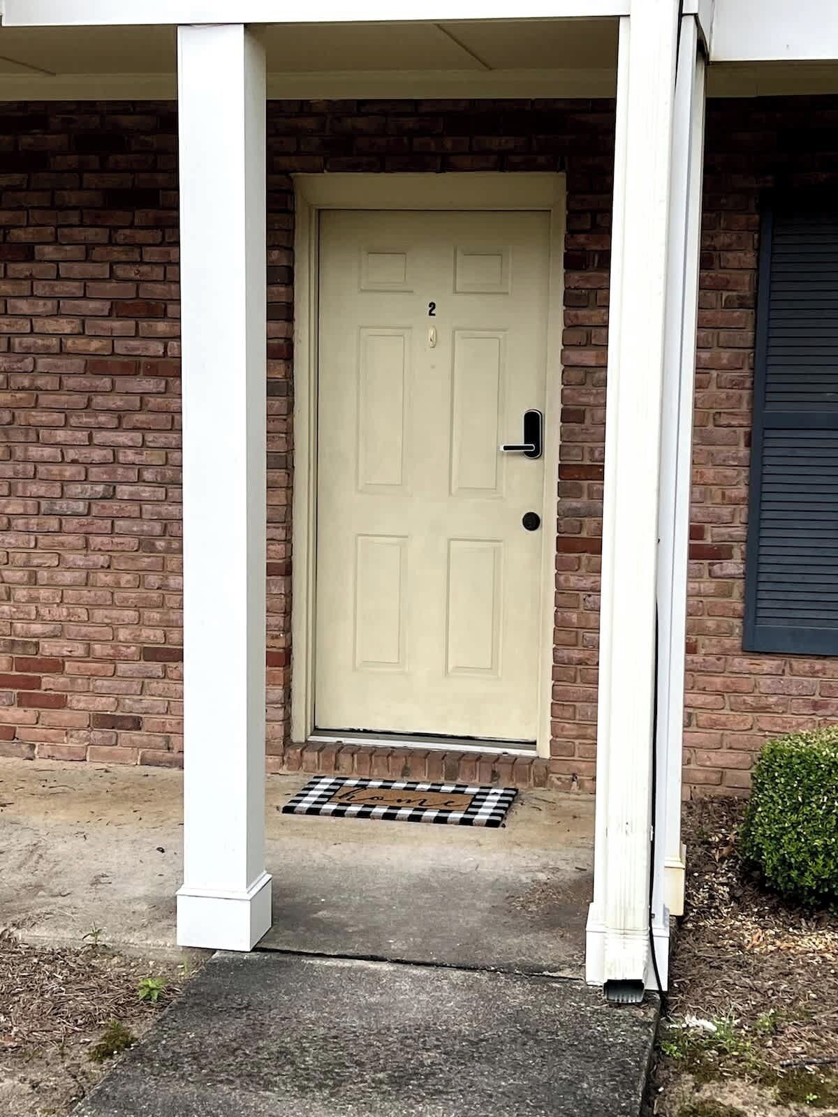 Front door with welcoming patterned doormat and secure keypad 