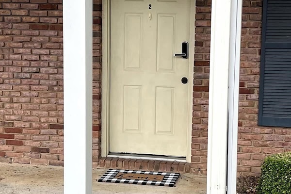 Front door with welcoming patterned doormat and secure keypad