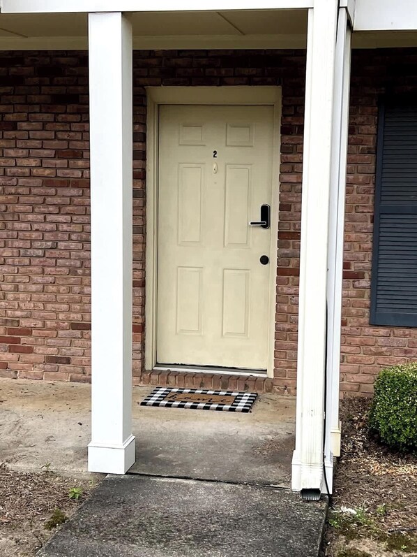 A beige door with a number '2' above it, set in a brick wall with a small overhang above.