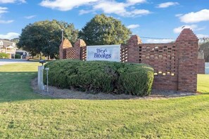A sign for 'The Brooks' with a brick wall and a well-maintained lawn.