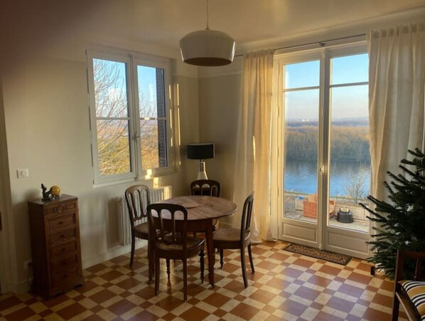 Enjoy meals in this cozy dining area with a round table and four chairs, a wooden cabinet, and a lamp.