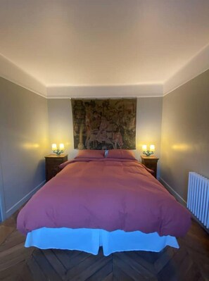 Classic bedroom with a large bed, bedside tables, and a textured wall tapestry.