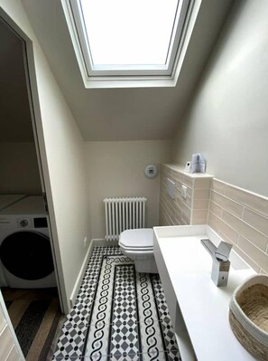 Features a skylight, white toilet, sink, and radiator.