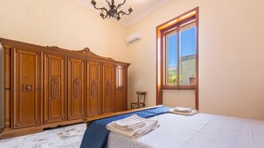 A bedroom with a large wooden wardrobe, a bed with a blue bedspread, and a window with a view of the outside. - 3611 Casa di Paolo by Barbarhouse (Campi Salentina)