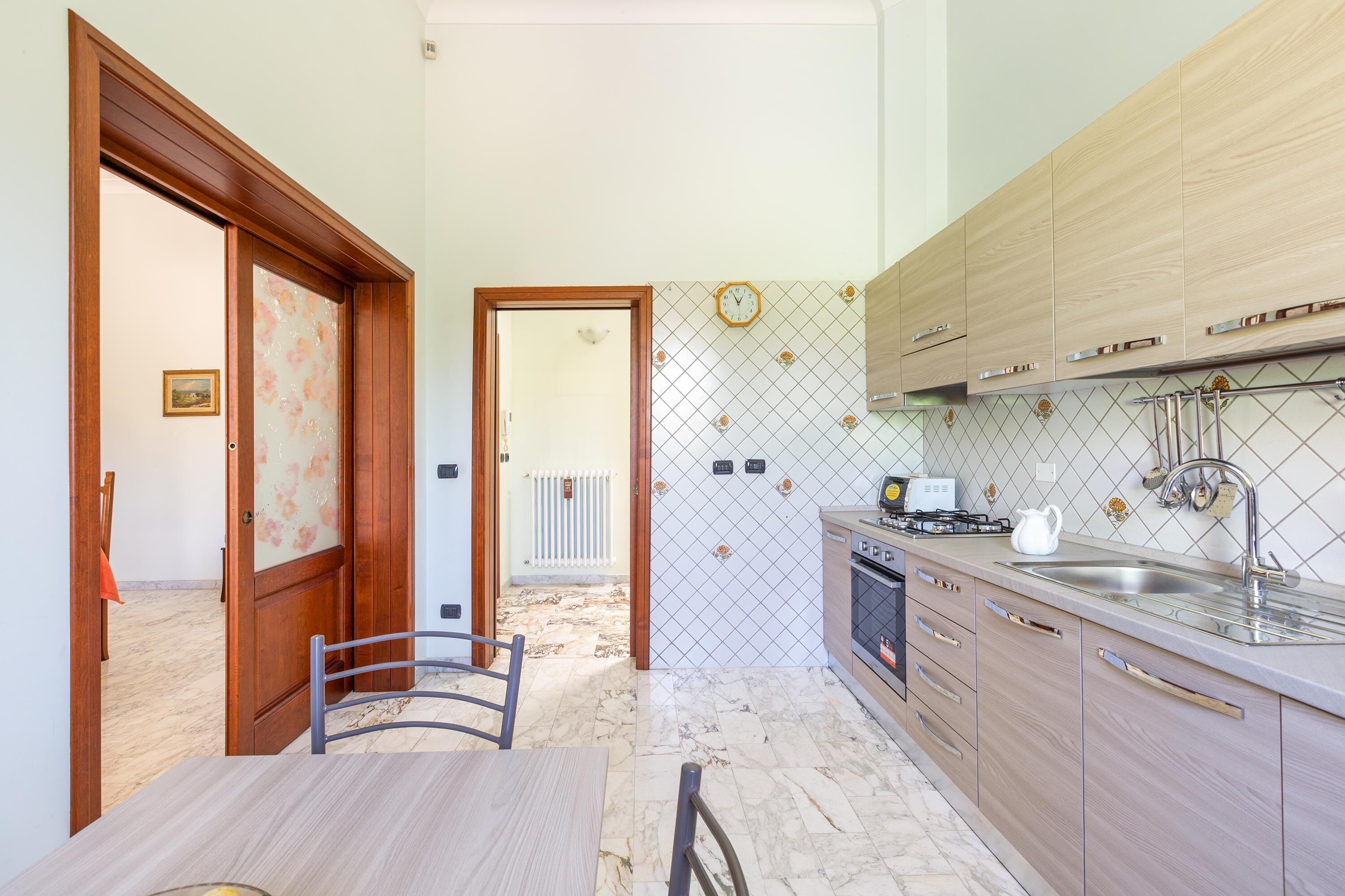 A kitchen with wooden cabinets, a marble countertop, and a tiled backsplash.
