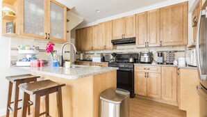 A kitchen with wooden cabinets, a stainless steel sink, a stove, and a refrigerator.