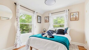 A bedroom with a bed, curtains, a window, and a painting on the wall.