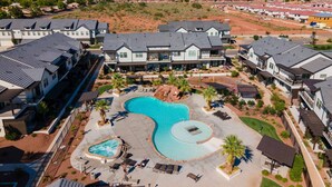 Un resort con diversi edifici, una piscina centrale e montagne sullo sfondo.