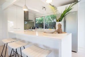 A modern kitchen with a large island, bar stools, and a large window.