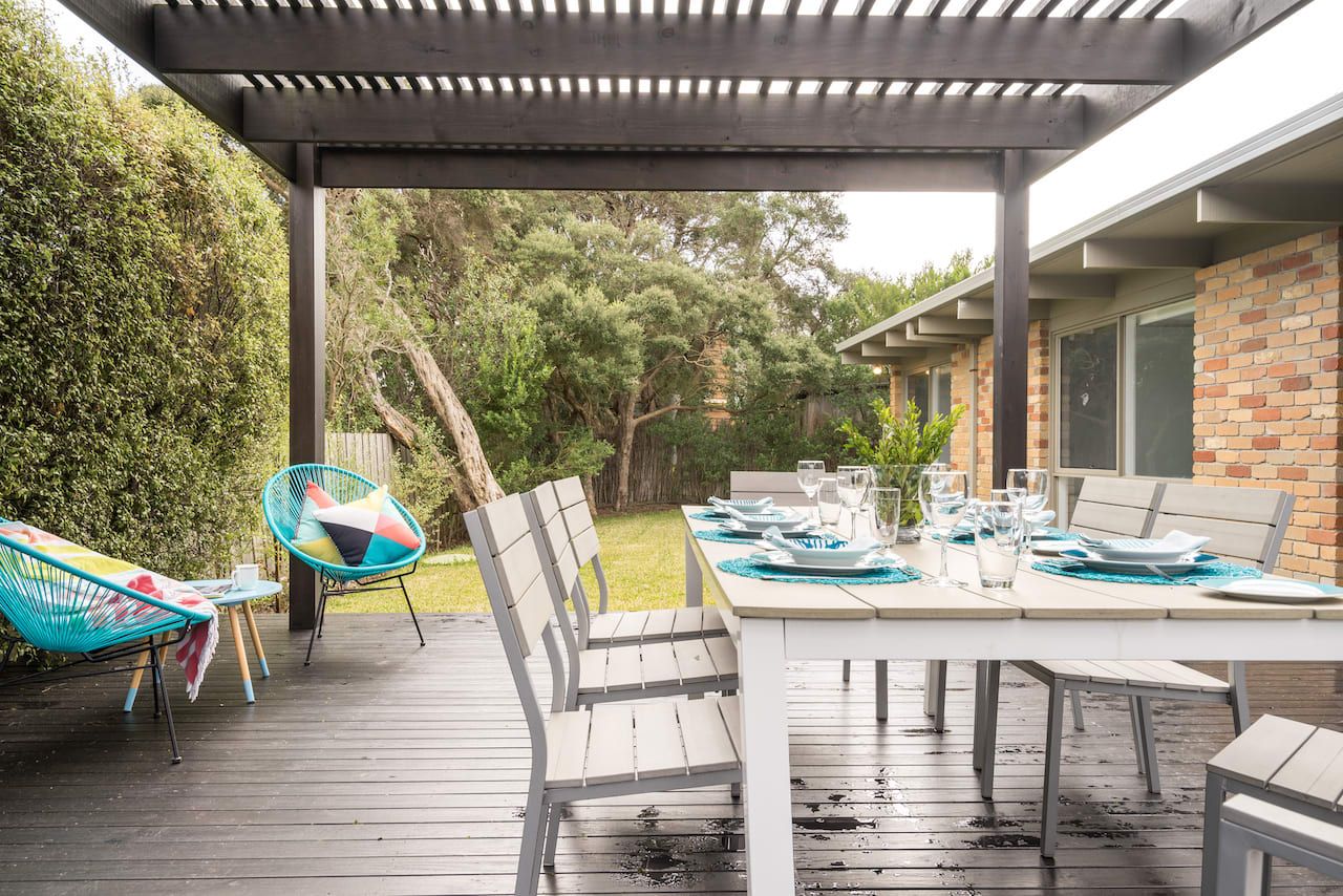 Eine Terrassengruppe im Freien mit Esstisch, Stühlen und einer Pergola.