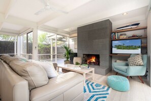 A modern living room with a fireplace, a sofa, a coffee table, and a television.