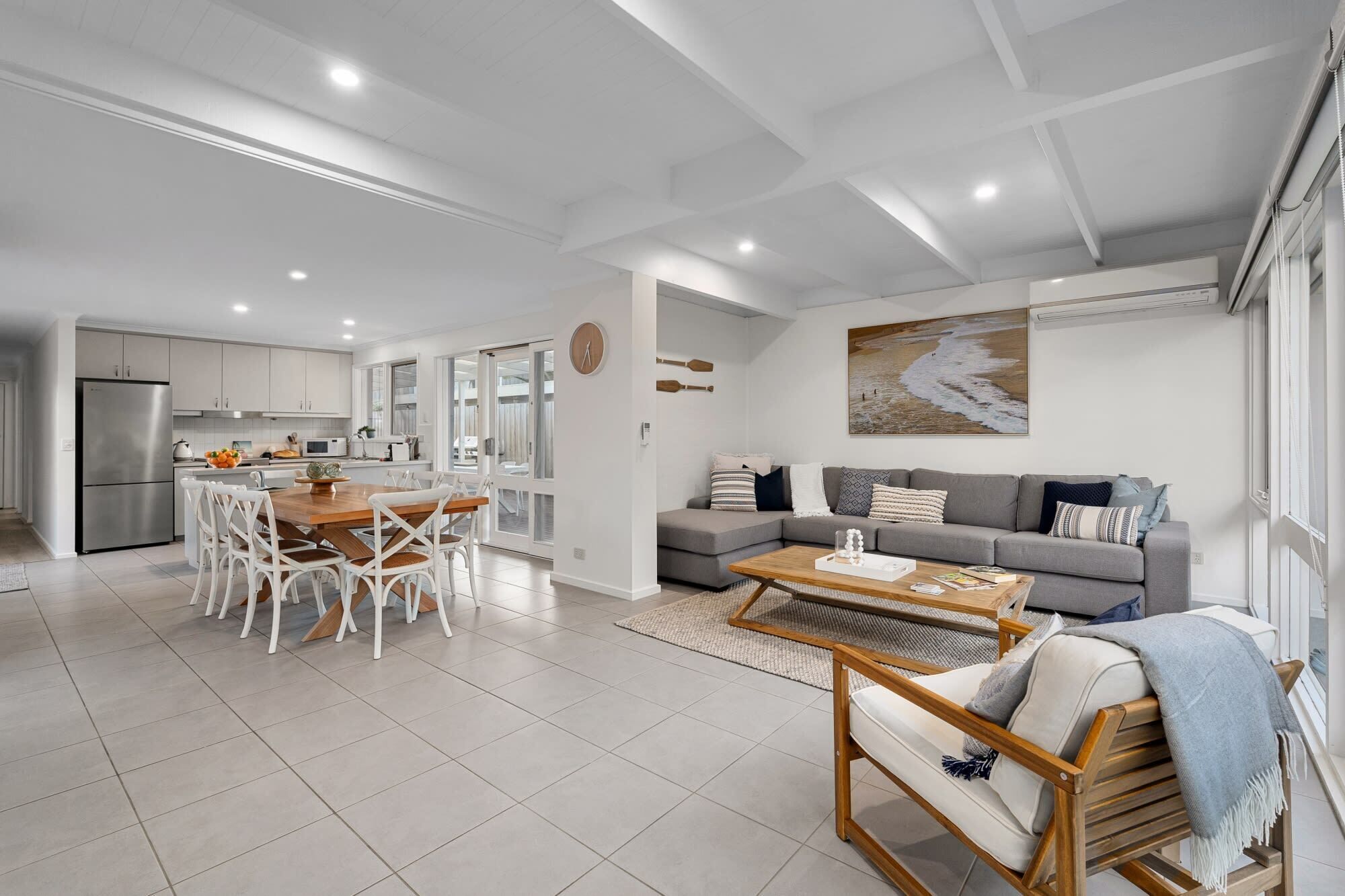 Un espacio habitable moderno con cocina, comedor y zona de estar con sofá y mesa de centro.
