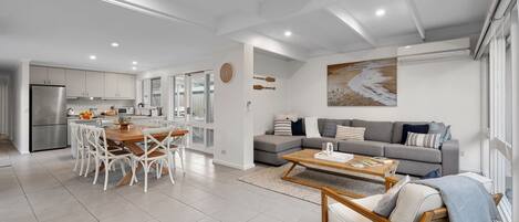 Un espacio habitable moderno con cocina, comedor y zona de estar con sofá y mesa de centro.