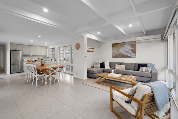A modern living space with a kitchen, dining area, and a seating area with a sofa and coffee table.