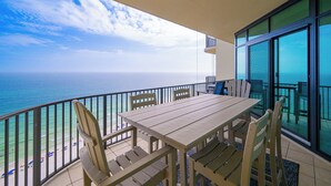 Een balkon met een tafel en stoelen, met uitzicht op een strand en de oceaan.