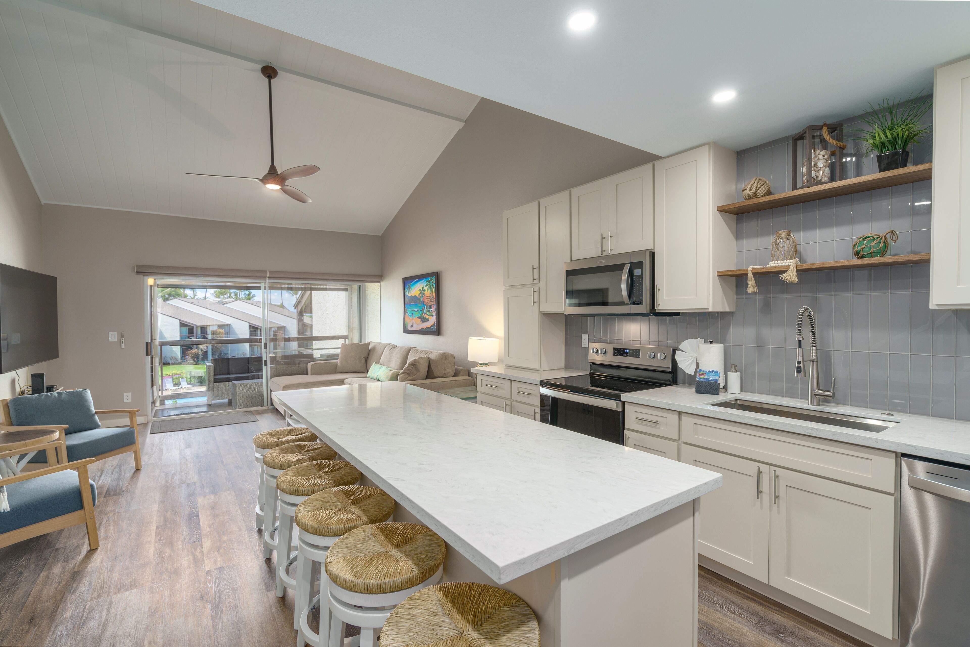 A modern kitchen with a central island, white cabinets, and a grey backsplash.