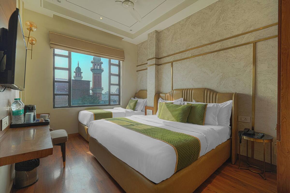 A hotel room with a large bed, two bedside tables, a desk, and a view of a historic building.